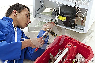 Repairman makes refrigerator appliance troubleshooting and maintenance Stock Photo