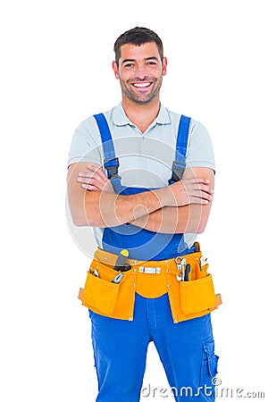 Repairman in overalls wearing tool belt standing arms crossed Stock Photo