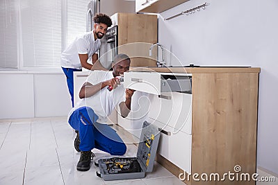 Repairmen Fixing The Wooden Cabinet In The Kitchen Stock Photo