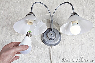 Replacing the bulbs in wall lights, hand holds LED lamp. Stock Photo