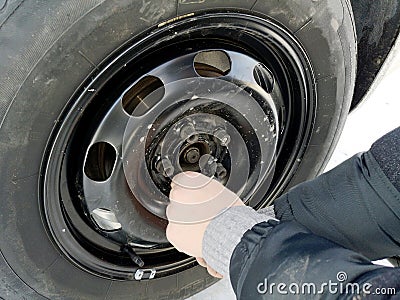 Punched and flat tire on the road. Replacing the wheel with a jack by the driver Stock Photo