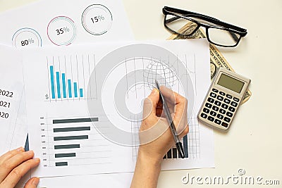 Reports and histograms on paper on the table in the hands of a girl, analytics and statistics on paper, business Stock Photo