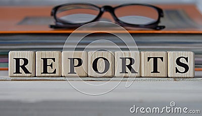 REPORTS - word on wooden cubes on the background of a folder with documents and glasses Stock Photo