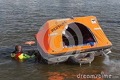 Rescue worker showing life raft in harbor Urk, the Netherlands Editorial Stock Photo