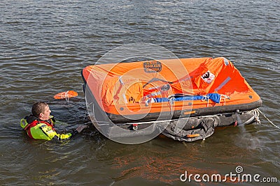 Rescue worker showing life raft in harbor Urk, the Netherlands Editorial Stock Photo