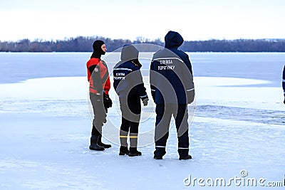 Rescuers in uniform and diving suit are on duty on the frozen river during winter fishing and sport events. Rescue service Editorial Stock Photo