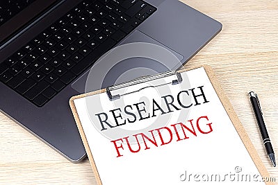 RESEARCH FUNDING text written on a paper clipboard on laptop Stock Photo