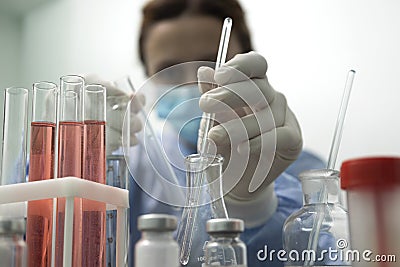 Closeup of lab tubes,flasks and woman scientist who undertaking research Stock Photo