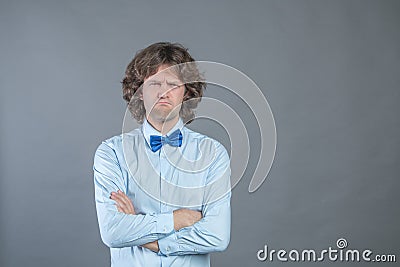 Resentful man with arms folded over gray background in studio shot and offended looked at camera. Upset guy looking very Stock Photo