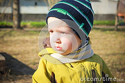 Resentful, sad little boy sitting in the garden on the Playground. Portrait of a sad, hurt child.. Stock Photo