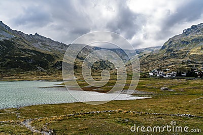 Reservoir lake in the Italian Alps near mountain pass Splügen with big mountain range and italian mountain village Stock Photo