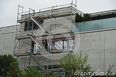 Residential building, modern and small with scaffolding on one of the walls to repair the terraced roof Stock Photo
