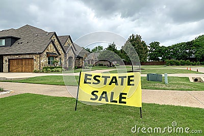 Residential house with road and neat lawn in front, big yellow sign with estate sale inscription. Stock Photo