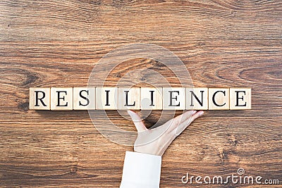 Resilience word on wooden building blocks with supporting hand Stock Photo