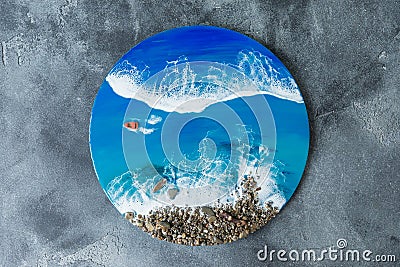 Resin art round painting. Epoxy art composition with blue ocean waves, boat and stones beach. Flat lay, top view Stock Photo