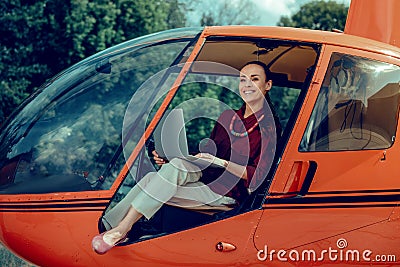 Resolute cheerful lady in light pants and red shirt resting in helicopter Stock Photo