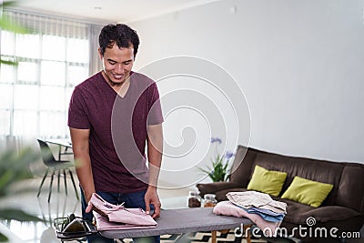 responsible husband busy with house work, irones his shirt in morning Stock Photo