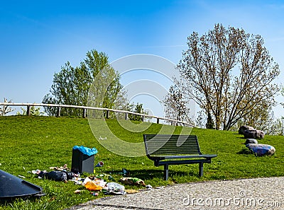 Rest area in a park on which people have thoughtlessly throw their trash next to the trash can on the lawn Editorial Stock Photo