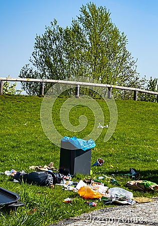 Rest area in a park on which people have thoughtlessly throw their trash next to the trash can on the lawn Editorial Stock Photo