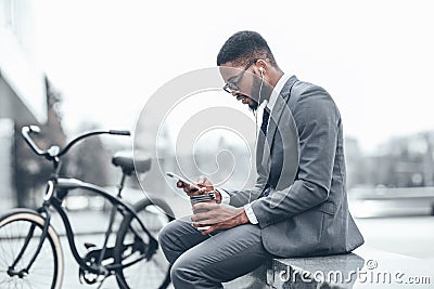Rest during break. Afro businessman using smartphone outdoors Stock Photo