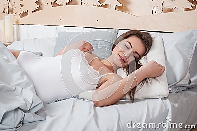 Rest, sleeping, comfort and people concept - young woman stretching in bed at home bedroom. Stock Photo