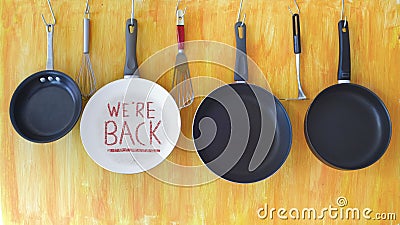 Restaurant announcing reopening after corona virus lockdown, kitchen utensils and message on frying pan,back to business Stock Photo