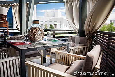 A restaurant with beautifully furnished interiors, comfortable armchairs and served tables on a spacious outdoor terrace Stock Photo