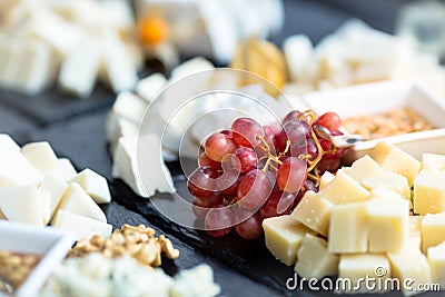 Restaurant cheese plate. Various types of cheeses with grape on black slate stone. Close up image with selective focus Stock Photo