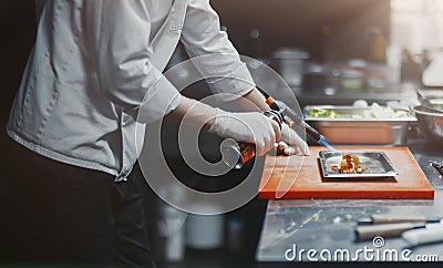 Restaurant Chef cook preparing salmon filet flambe in open kitchen Stock Photo