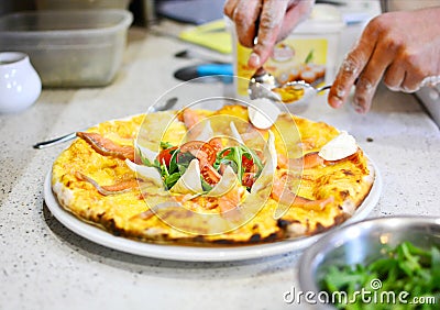 Restaurant chef makes tasty italian pizza with salmon fish. Stock Photo