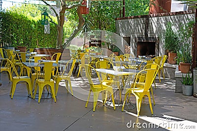 Restaurant courtyard with yellow chairs under the trees Stock Photo