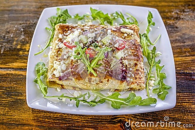 Fresh, enticing Greek Mediterranean style crepe with tomatoes, cucumbers, onion, feta cheese, & arugula. Stock Photo