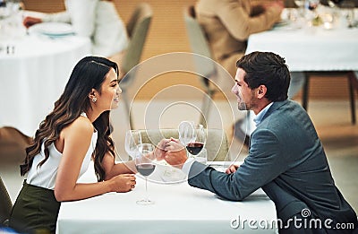 Restaurant, date and couple holding hands with wine for romantic dinner, relax and anniversary celebration. Relationship Stock Photo