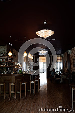 Restaurant in a modern style with textured walls and a parquet. There are wooden cheirs with tables, decorative wooden Editorial Stock Photo