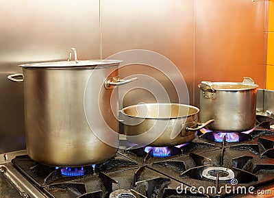 Restaurant pro kitchen with steel pans in fire Stock Photo