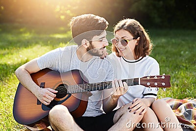 Restful couple of young people having relaxation outdoors enjoying pleasant moments and calm atmosphere. Romantic male with beard Stock Photo