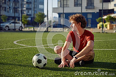 Restful father sitting on football stadium grass Stock Photo
