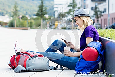 Resting blond female backpacker with mobile phone Stock Photo