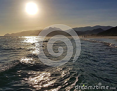 Restless sea waves with sunlight reflections and mountains Stock Photo