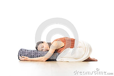 Restorative yoga with a bolster. Young sporty attractive woman in bright white yoga studio, lying on bolster cushion Stock Photo