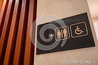 Restroom sign made of gold metal on black board hanging on wall Stock Photo