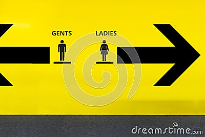 Restroom or Toilet Sign with Arrow on Yellow Wall Stock Photo