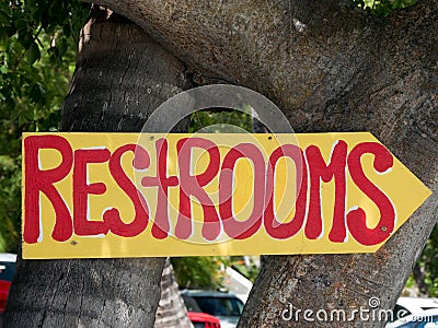 Restrooms sign with an arrow points toward a nature trail that leads to the bathroom Stock Photo