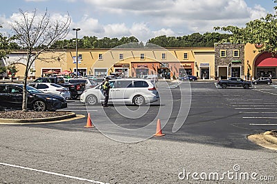 Retail strip mall Cars lined up outdoor curb event security officer social distancing Editorial Stock Photo