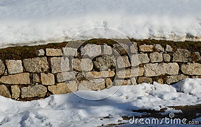 Retaining wall made of granite bricks by the road. the snow fit all around, only the wall remained visible in its beautiful textur Stock Photo