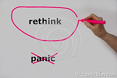 Rethink as an alternative to panic is written on a white wall by one hand, Rethink is circled with a pink pen and panic has been c Stock Photo