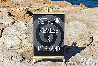 Rethink revise rebrand symbol. Concept word Rethink Revise and Rebrand on beautiful blackboard. Beautiful red stone background. Stock Photo