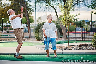 Retired couple having fun playing mini golf Stock Photo