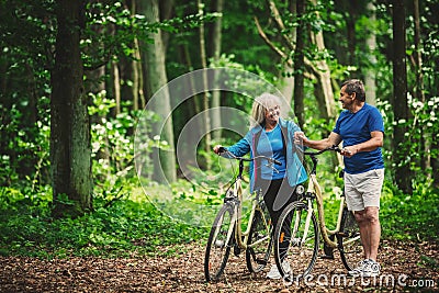 Retired couple walking with bikes in the forest. Stock Photo