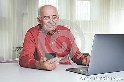 Retired man using computer technologies at home Stock Photo